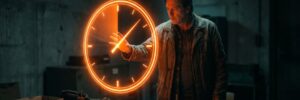 Man in a dark room touching a glowing neon clock projection.