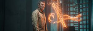 Man interacts with advanced security scanner emitting sparks and light.