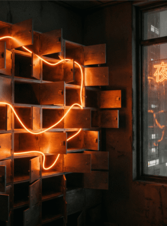 A wall of small steel deposit boxes with every door hanging open, one thread of orange light weaving through the compartments, a rainy neon city beyond the window