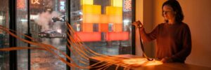 An office manager holds back one dark ribbon of light while the rest of the day's work streams out the door under a Mistral symbol sign