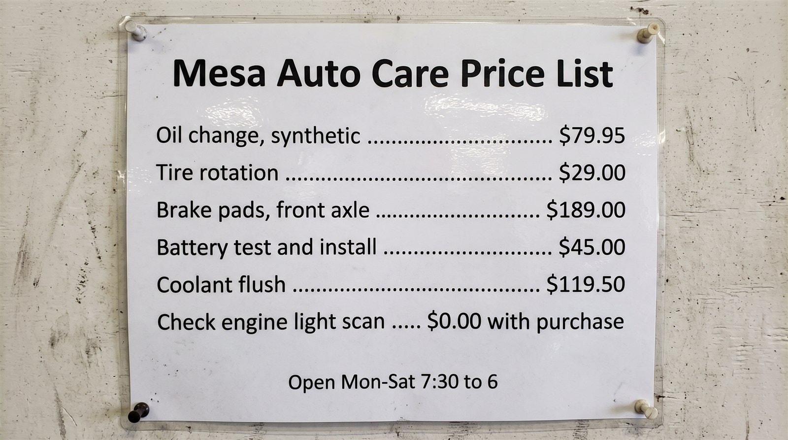 AI-generated test image of a laminated auto shop price list with six services and prices, all spelled and priced exactly as requested
